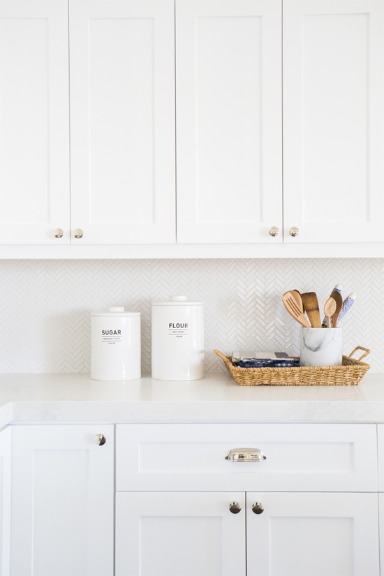 White kitchen cabinets and herringbone backsplash