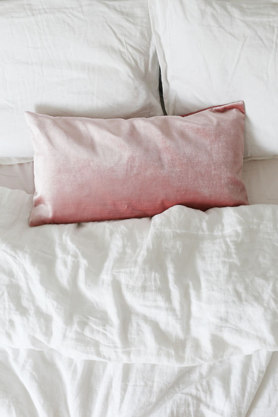 White linen bedding and a pink velvet pillow
